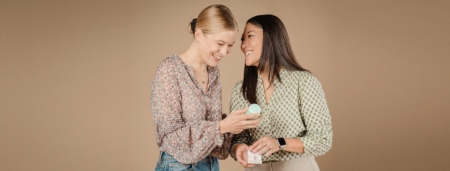 Founders of MeBloom (Alex & Niki) standing together and looking at the BeSilken Body Balm Stick in their hand